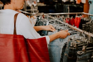 uma mulher está olhando para um rack de jeans