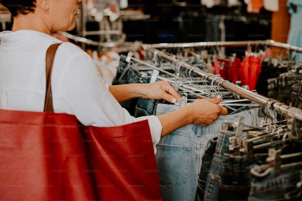 a woman is looking at a rack of jeans