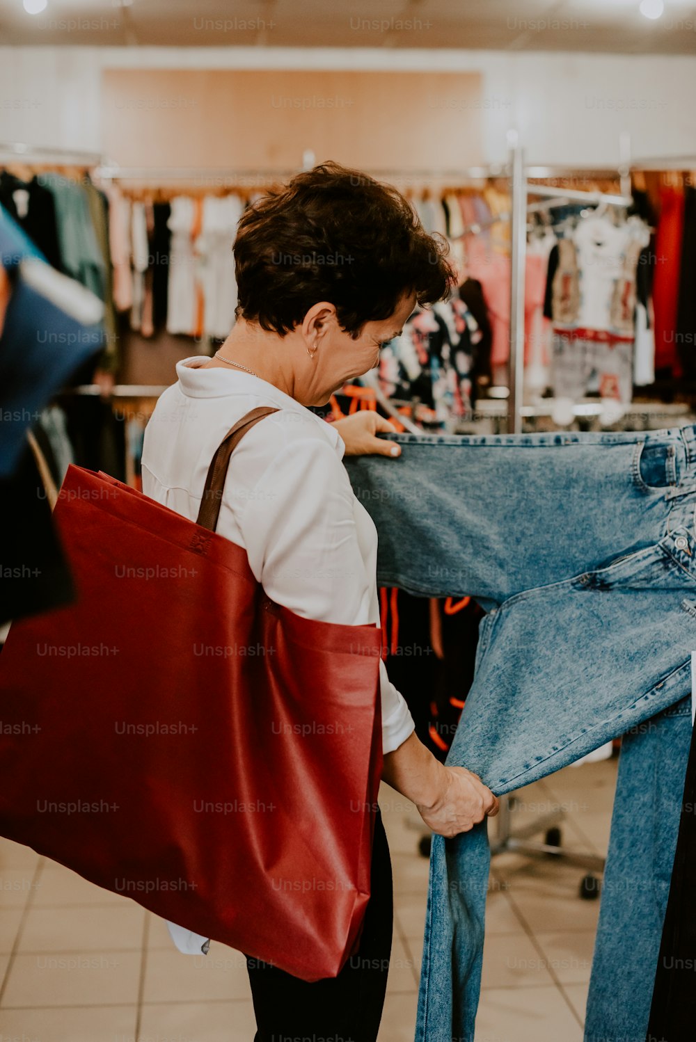 uma mulher olhando para um par de jeans em uma loja