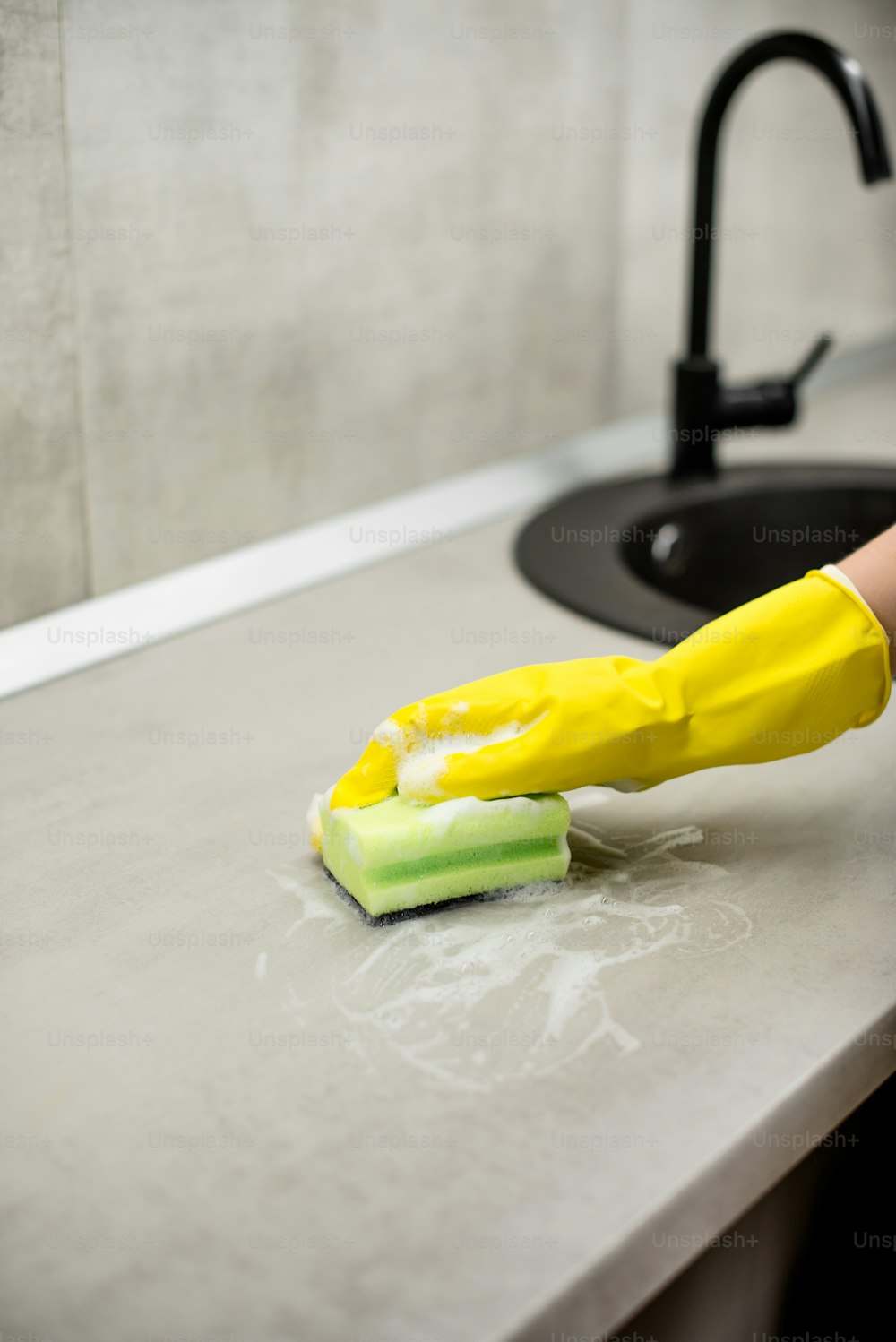 Eine Person mit gelben Handschuhen reinigt eine Theke