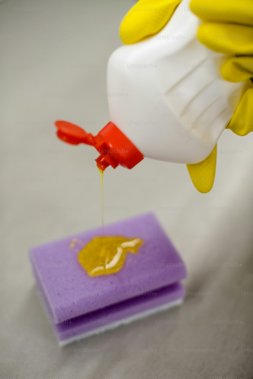 a person in yellow gloves pouring mustard onto a piece of paper