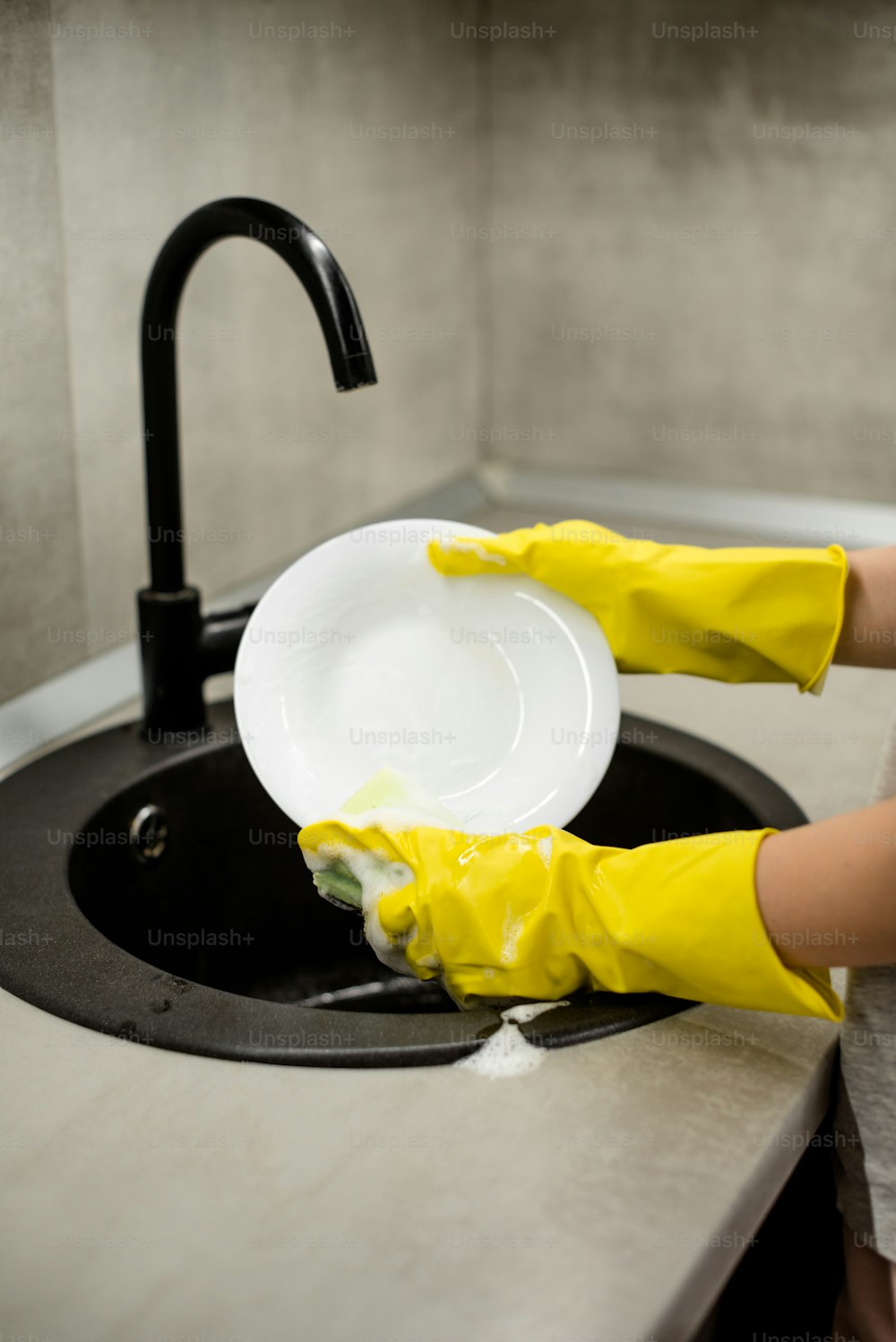 Una persona in guanti gialli che lava un piatto bianco