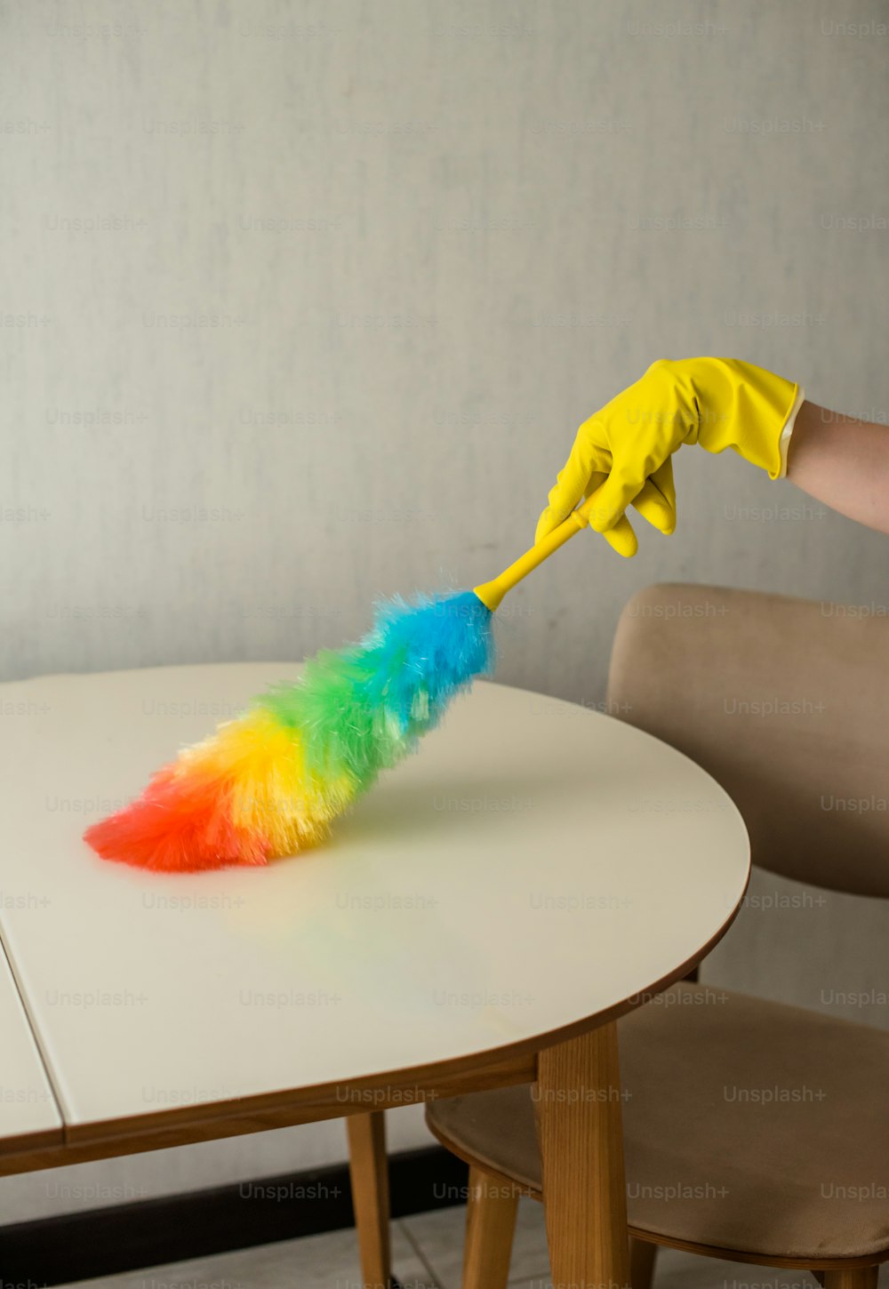una persona che pulisce un tavolo con uno spolverino colorato