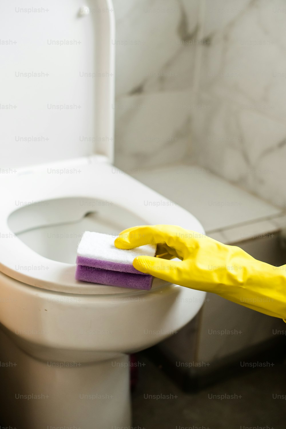 uma pessoa com luvas de borracha amarelas limpando um vaso sanitário