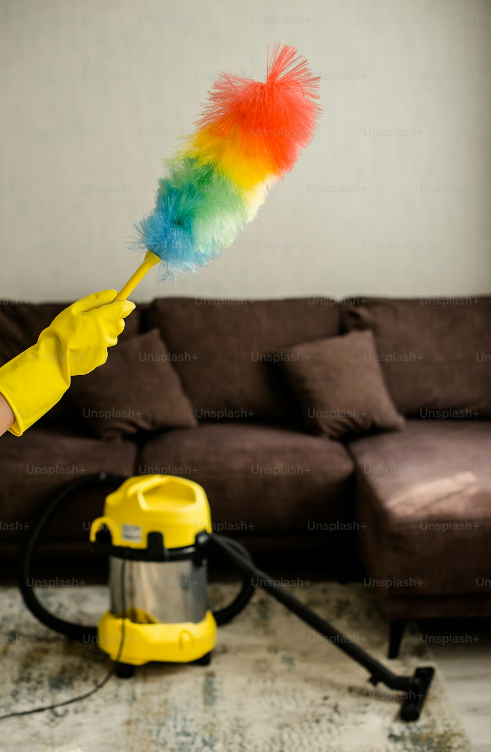 a person in yellow gloves holding a colorful duster