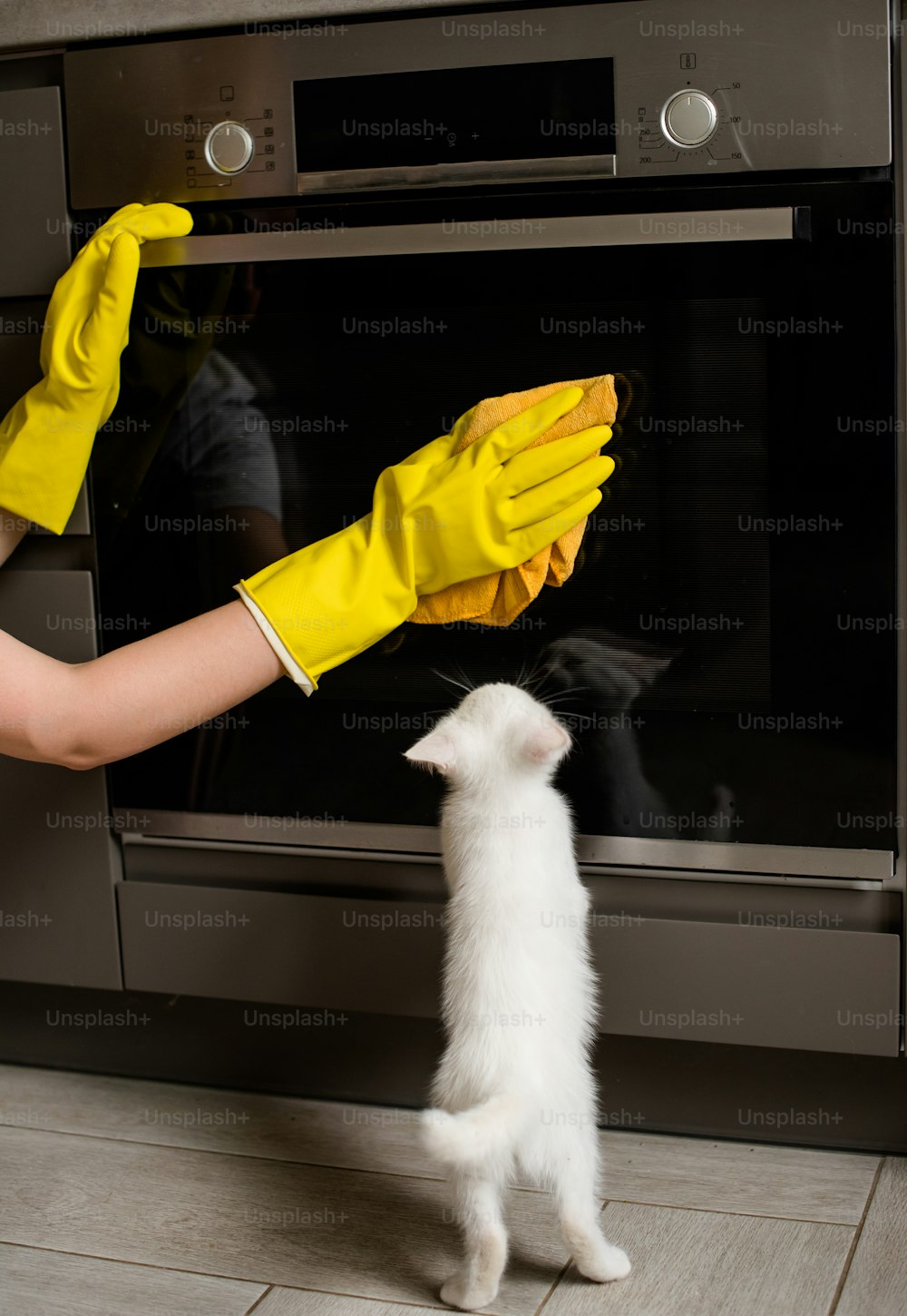 オーブンを掃除する黄色い手袋をはめた人