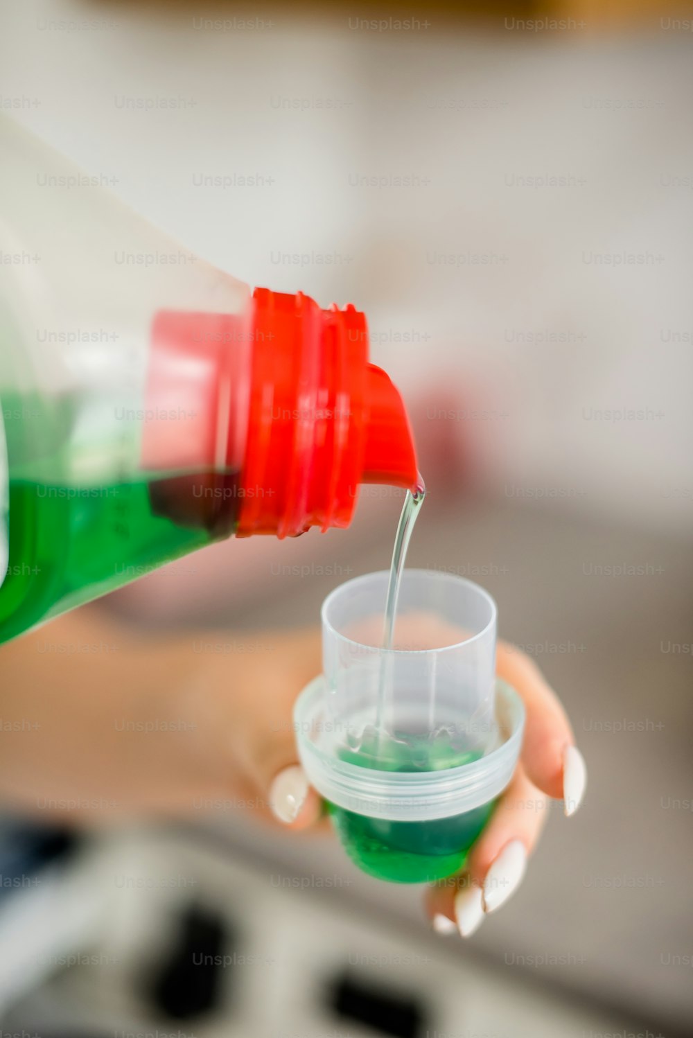 Eine Person gießt eine grüne Flüssigkeit in eine Tasse