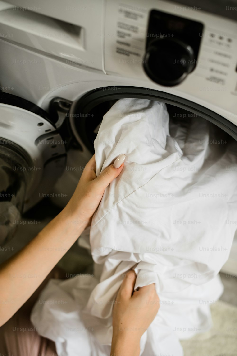 a woman is putting a cloth into a dryer