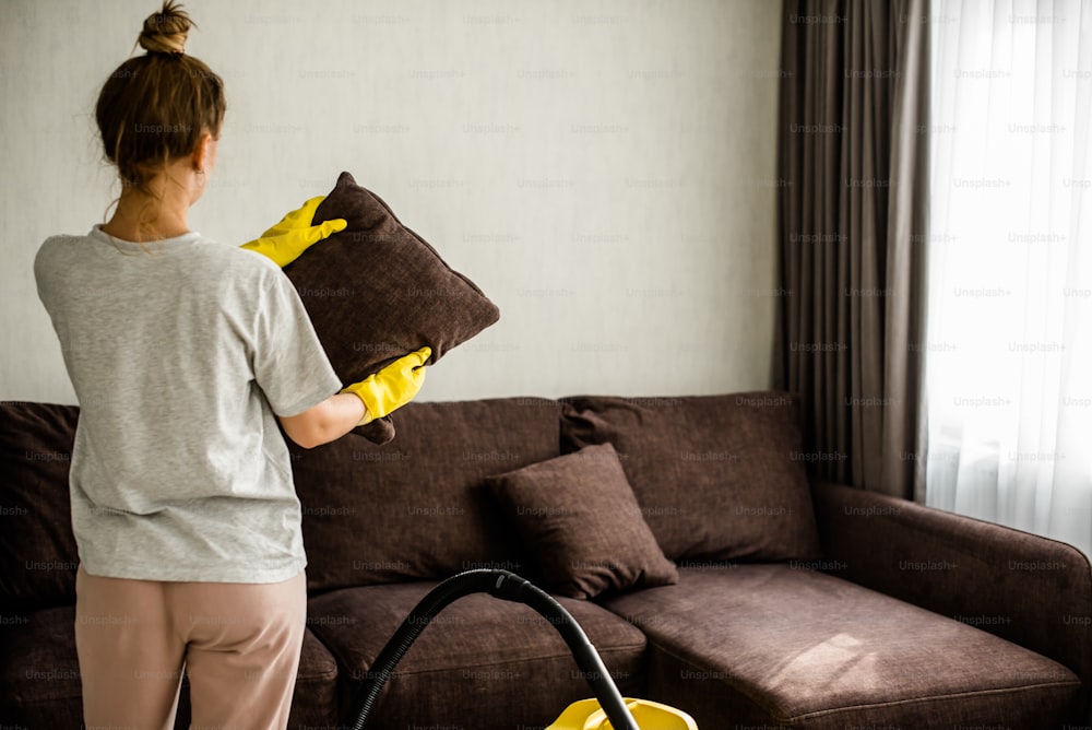 Una donna sta pulendo un soggiorno con un aspirapolvere