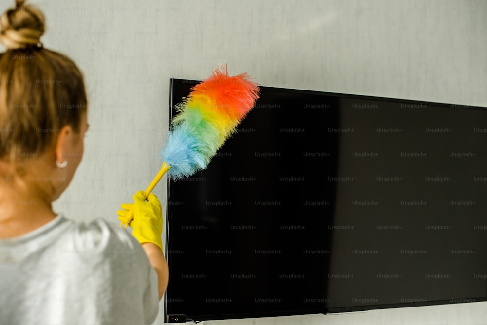 a woman is cleaning a flat screen tv