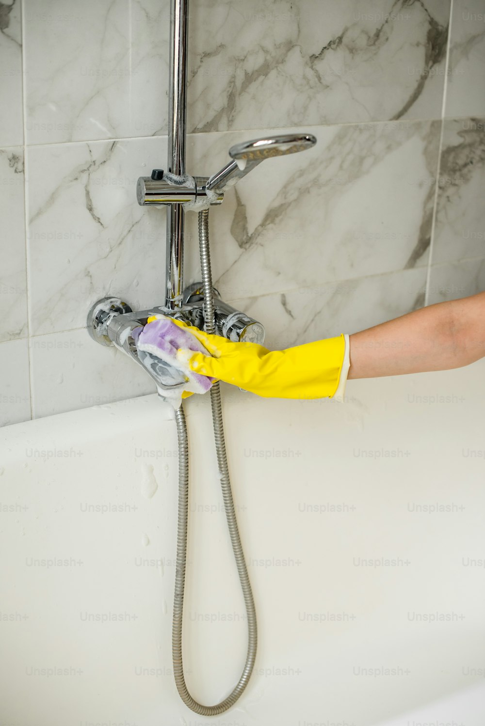 a person in yellow gloves is cleaning a bathtub
