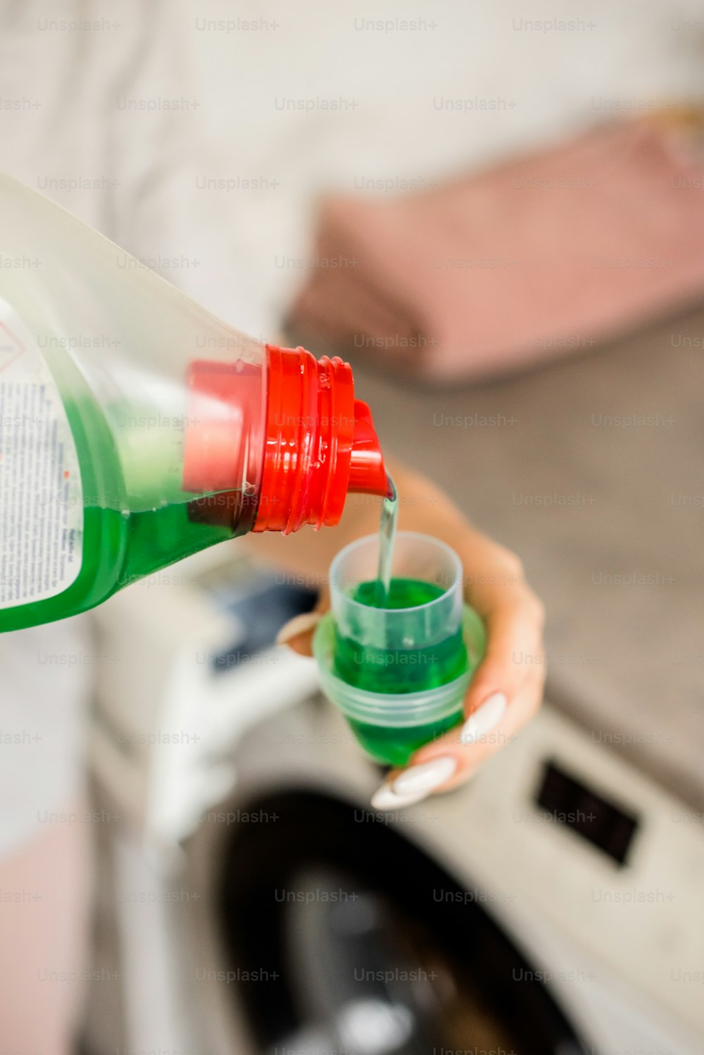 a person is pouring a green liquid into a cup