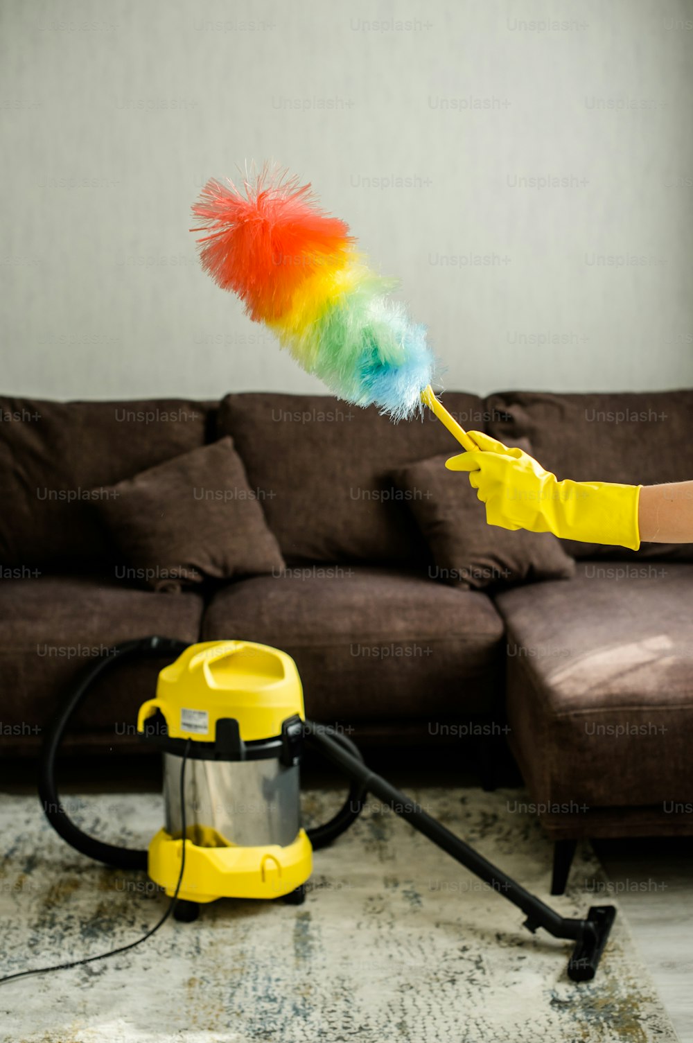 a woman in yellow gloves is cleaning a living room