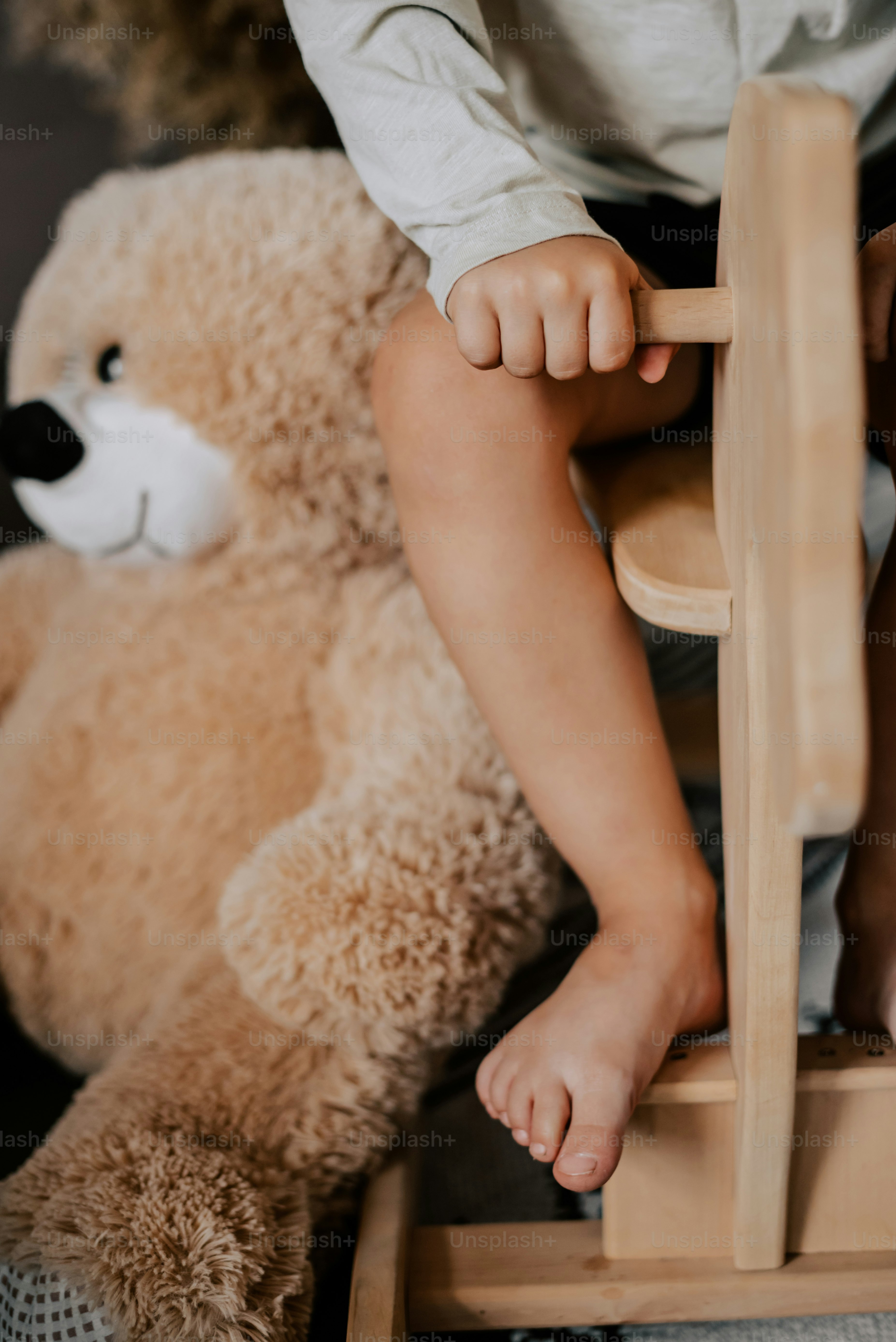 Ein kleiner Junge, der mit einem Teddybären auf einem Stuhl sitzt