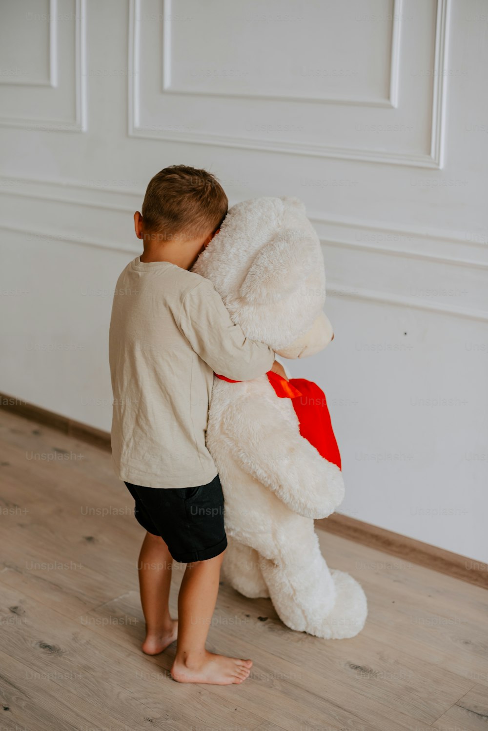 a young boy holding a large white teddy bear