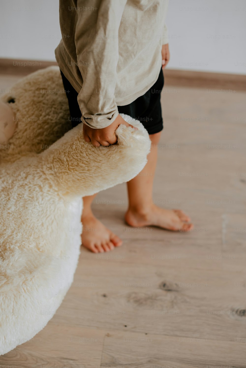a person holding a stuffed animal on a wooden floor
