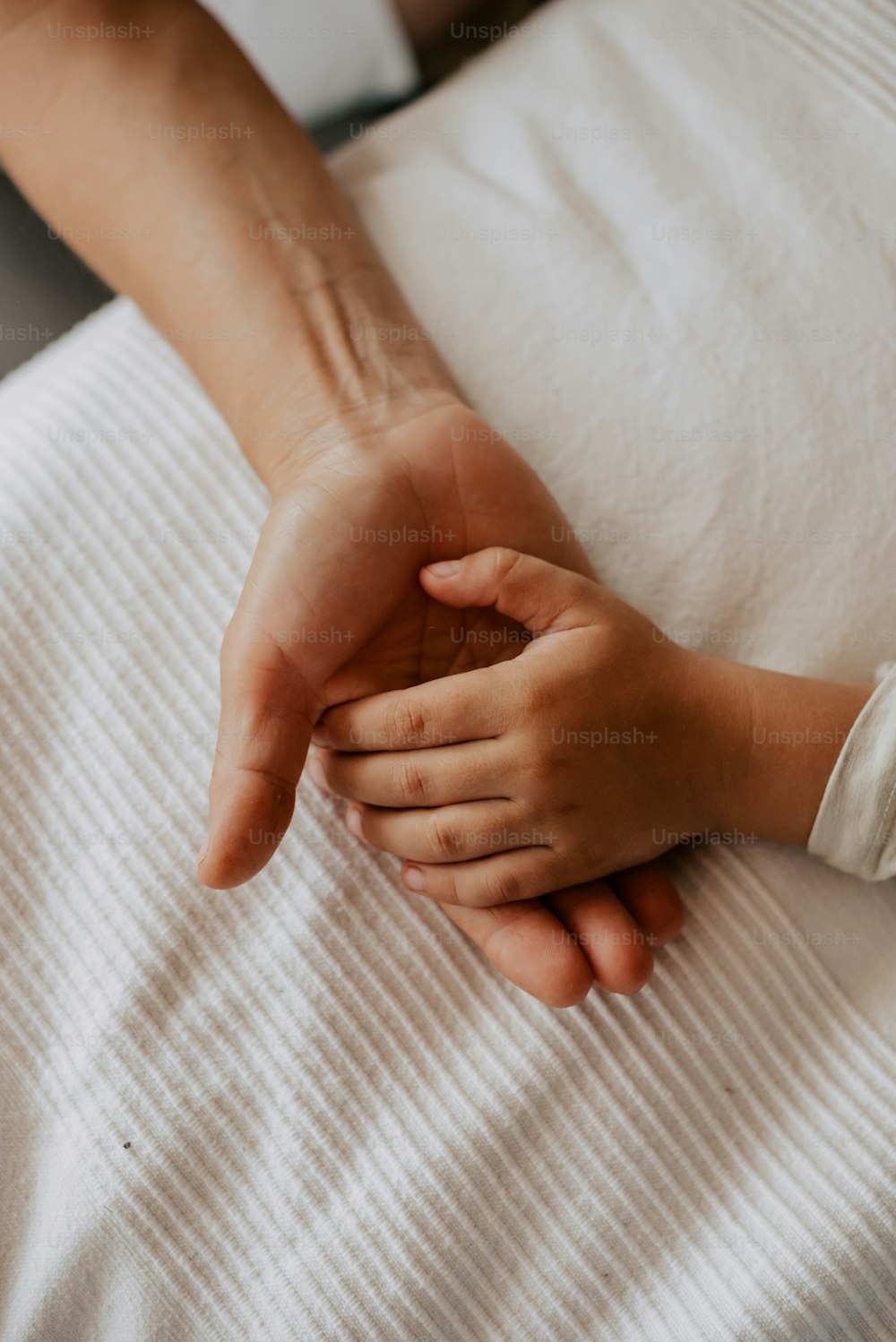 a person holding the hand of another person on a bed