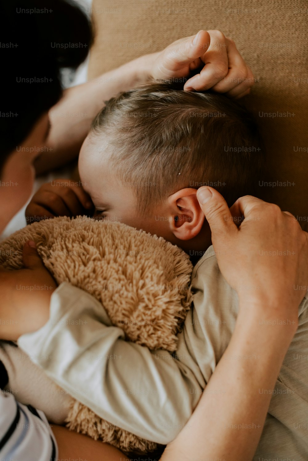 a woman is holding a baby and touching a teddy bear