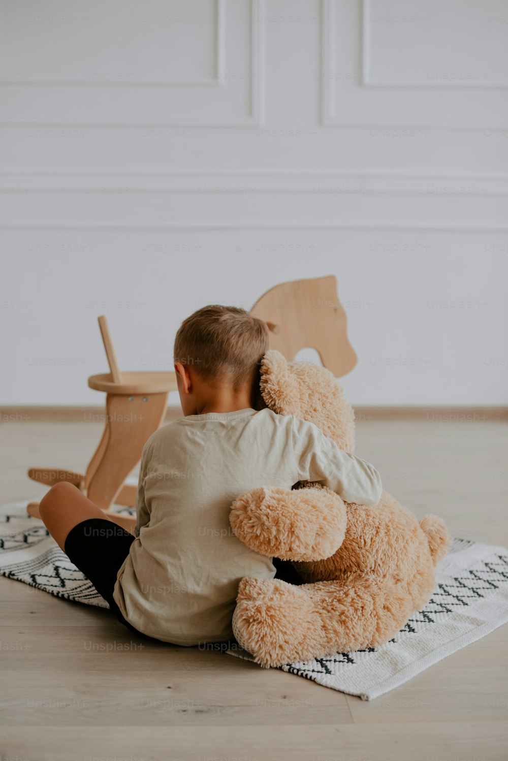 Un petit garçon assis par terre avec un ours en peluche