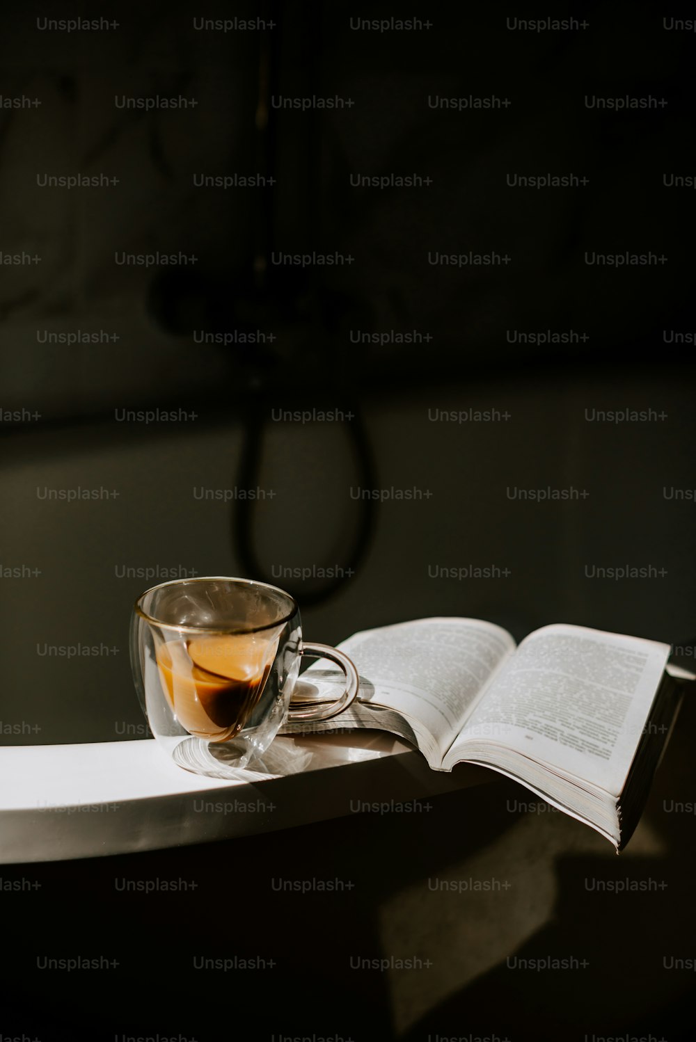 eine Tasse Tee und ein offenes Buch auf einem Tisch