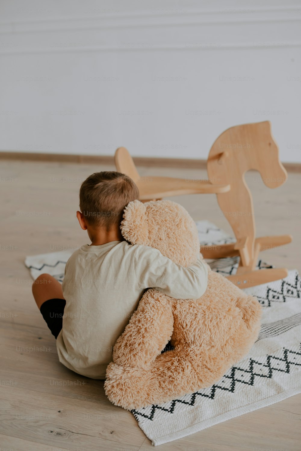 Un ragazzino seduto sul pavimento con un orsacchiotto