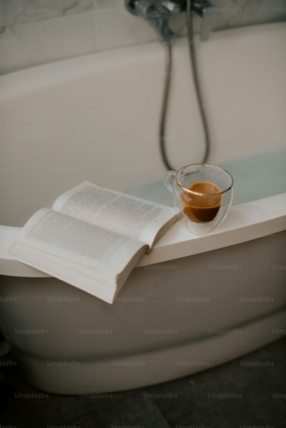 a cup of coffee and a book on a bathtub
