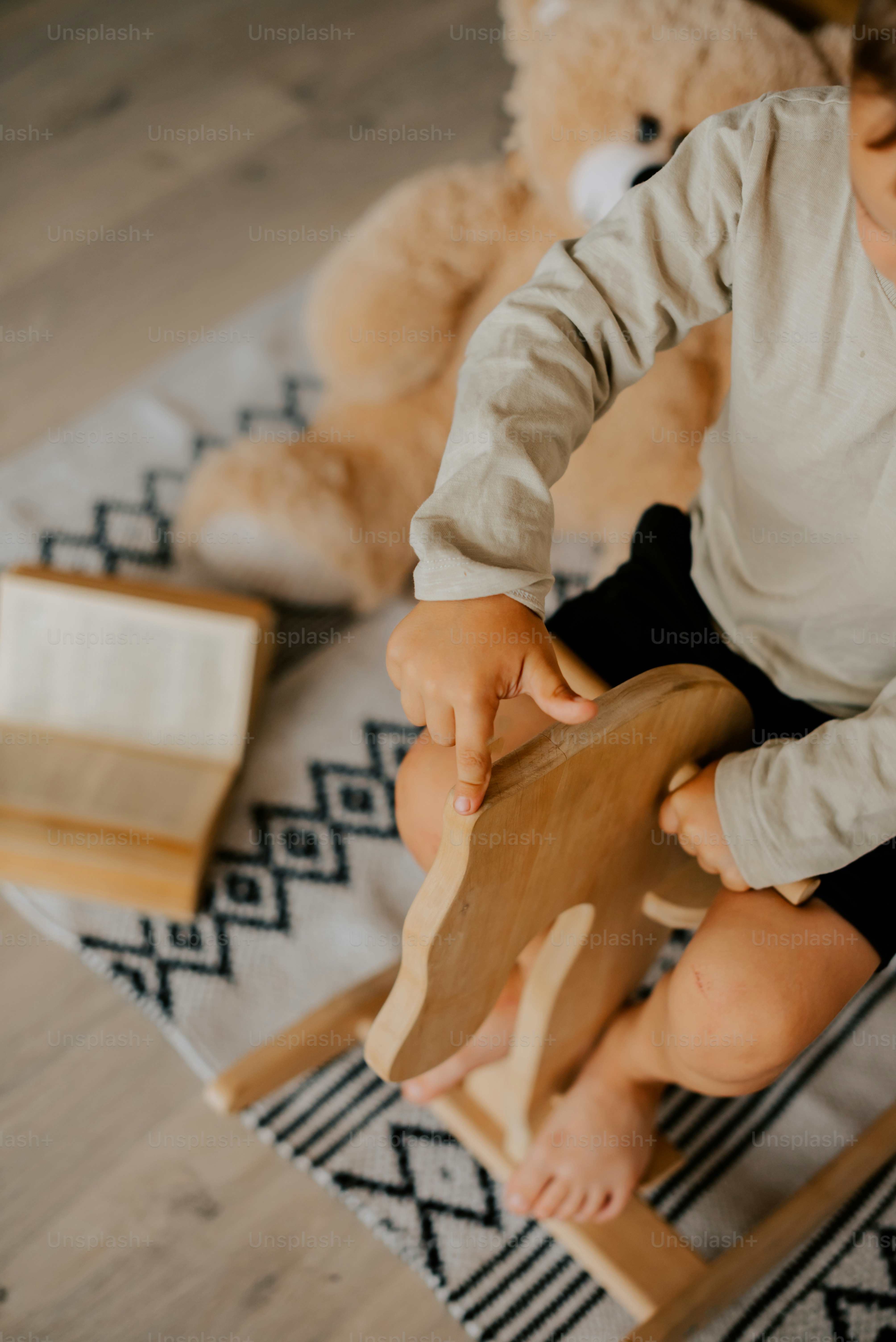 Ein kleiner Junge, der auf einem Stuhl sitzt und mit einem Holzspielzeug spielt