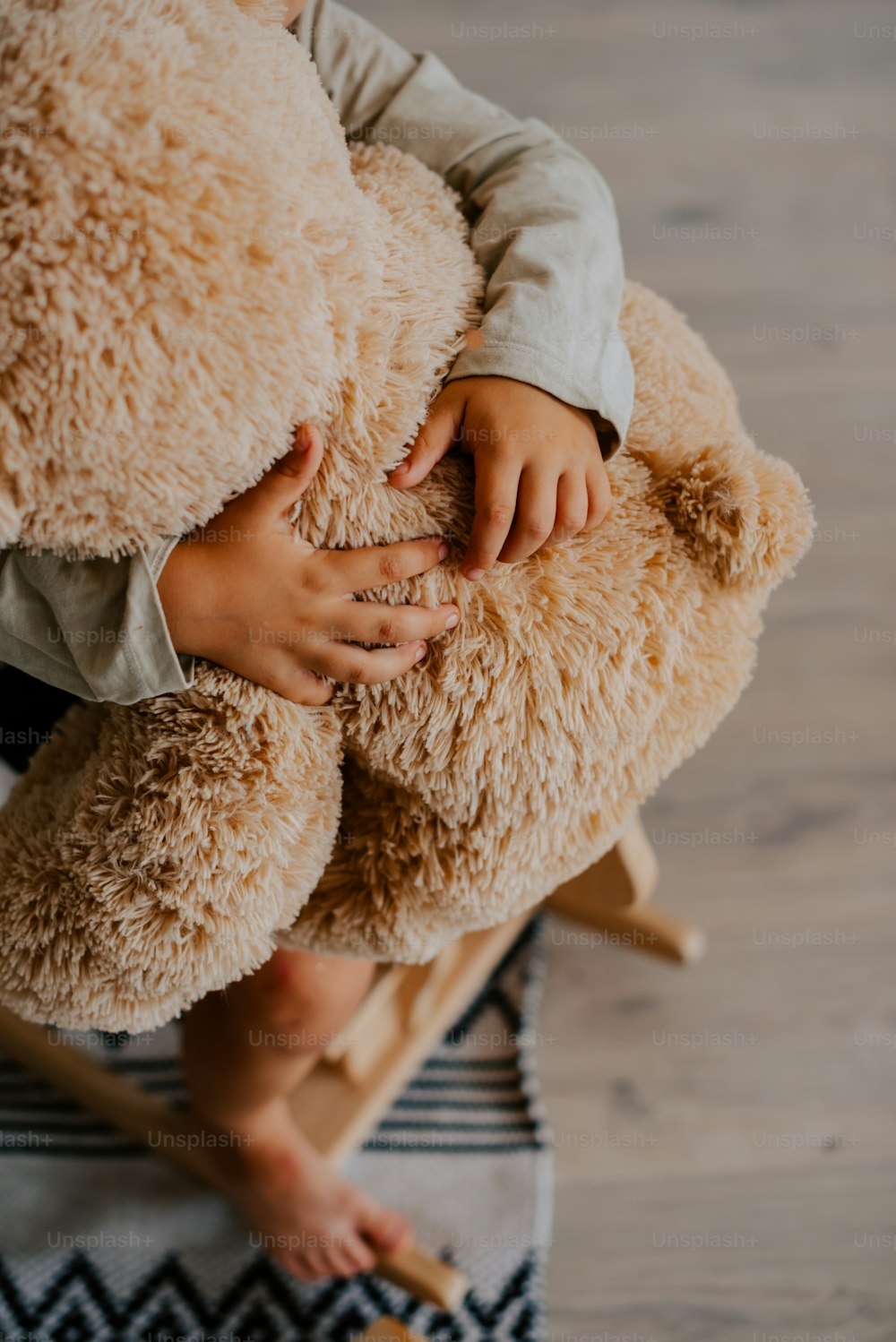 uma criança segurando um ursinho de pelúcia em cima de um tapete