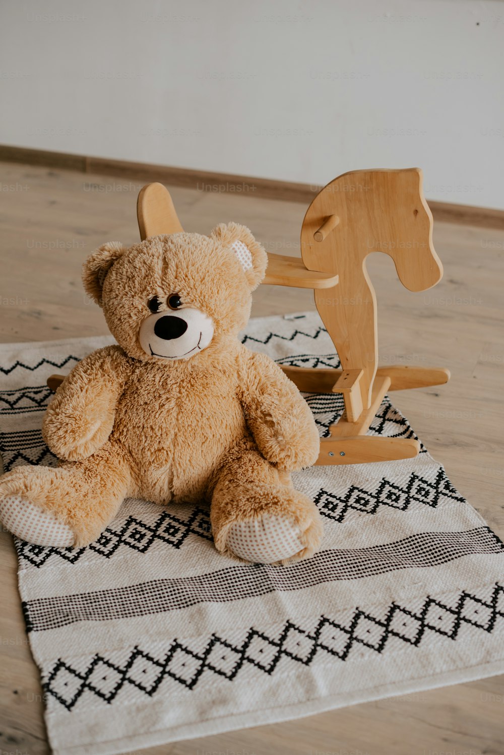 a brown teddy bear sitting on top of a rug