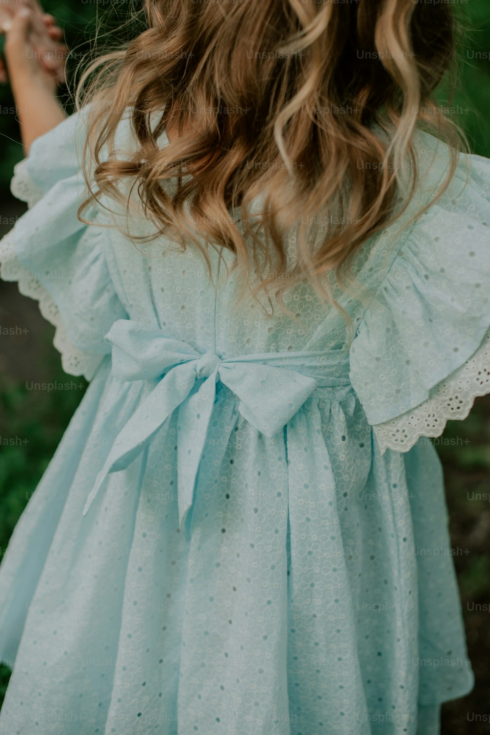 a little girl wearing a blue dress with a bow