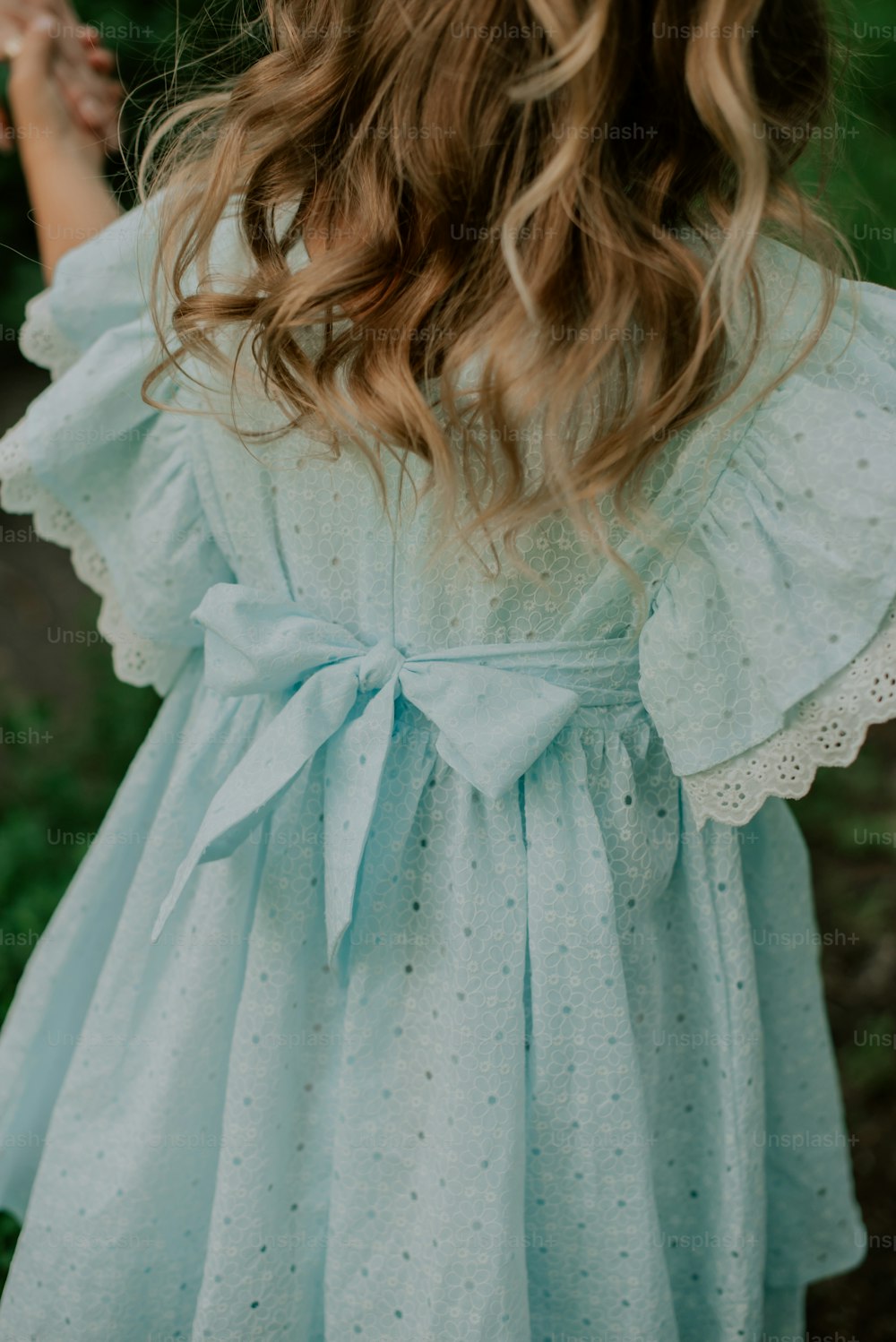 Una niña con un vestido azul con un lazo