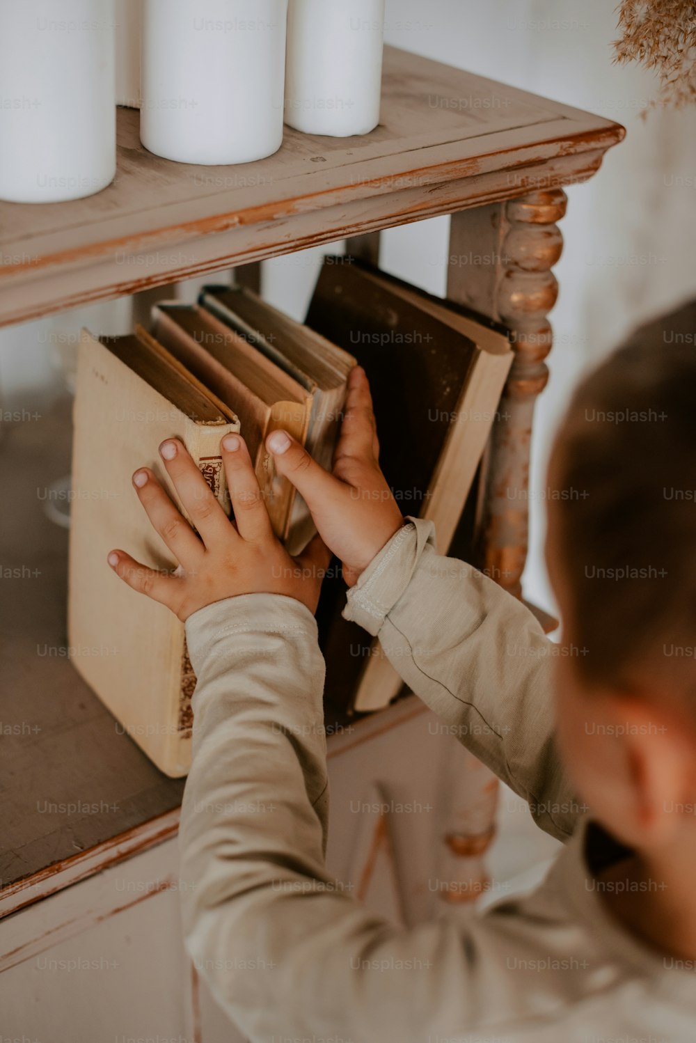 a young child reaching for a book on a shelf