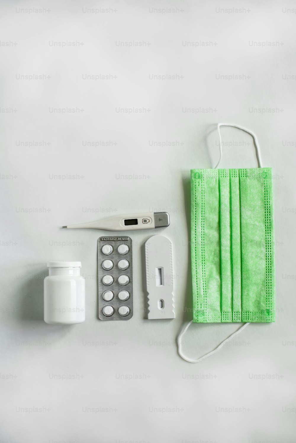 a medical kit with a green face mask, a thermometer, and a