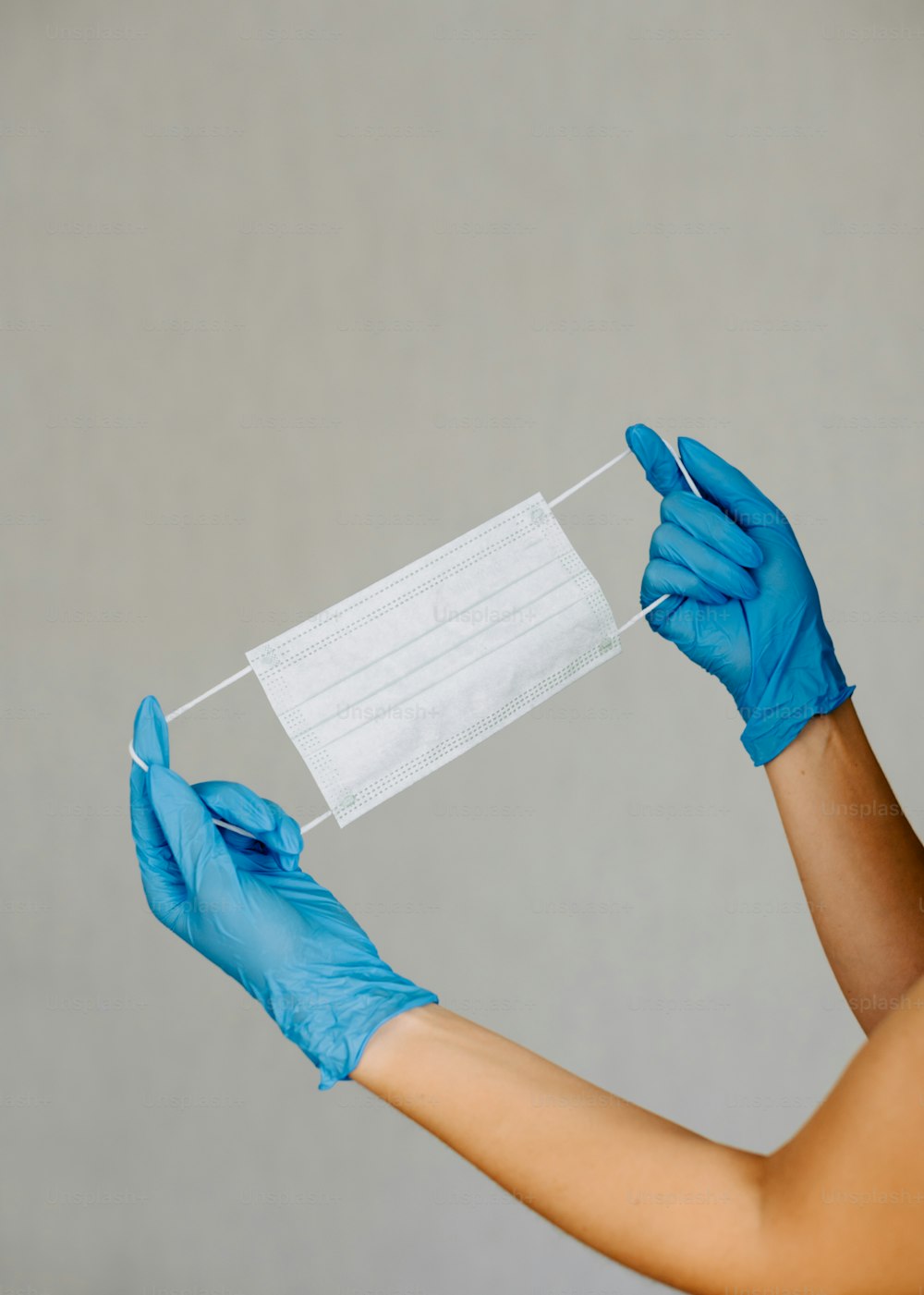 a woman wearing blue gloves and a face mask