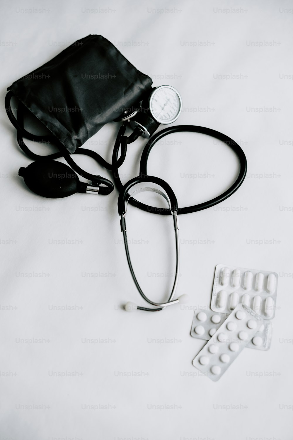 a doctor's stethoscope and pills on a bed
