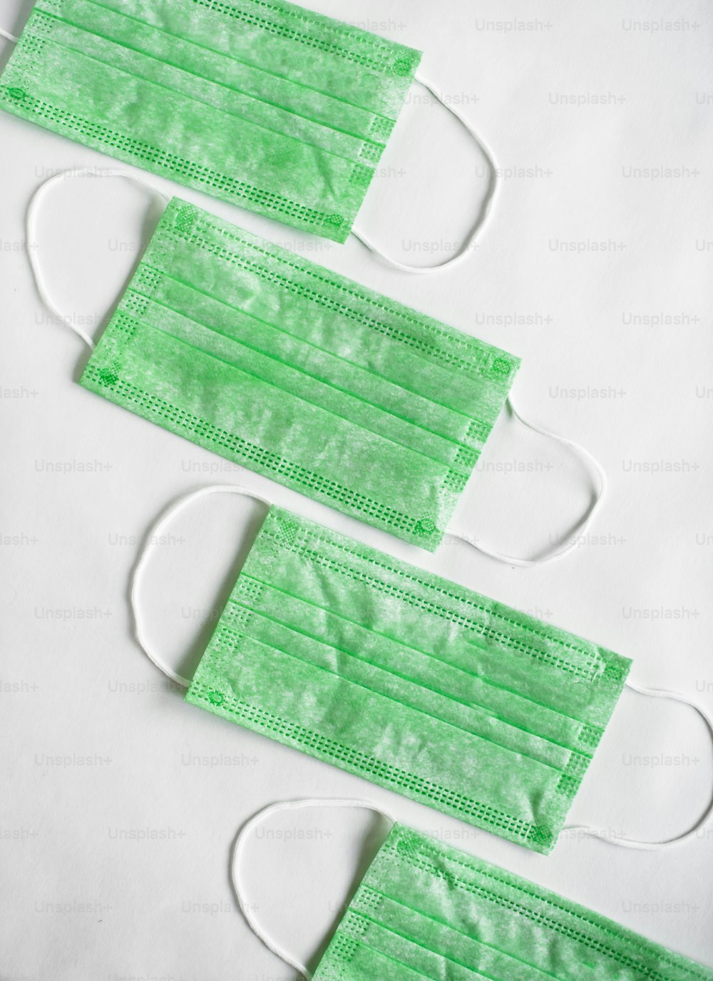 three green surgical masks on a white background