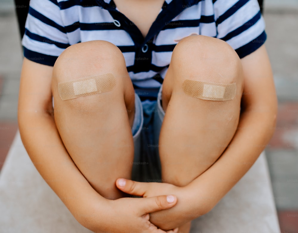 un jeune garçon avec des bandages sur le genou