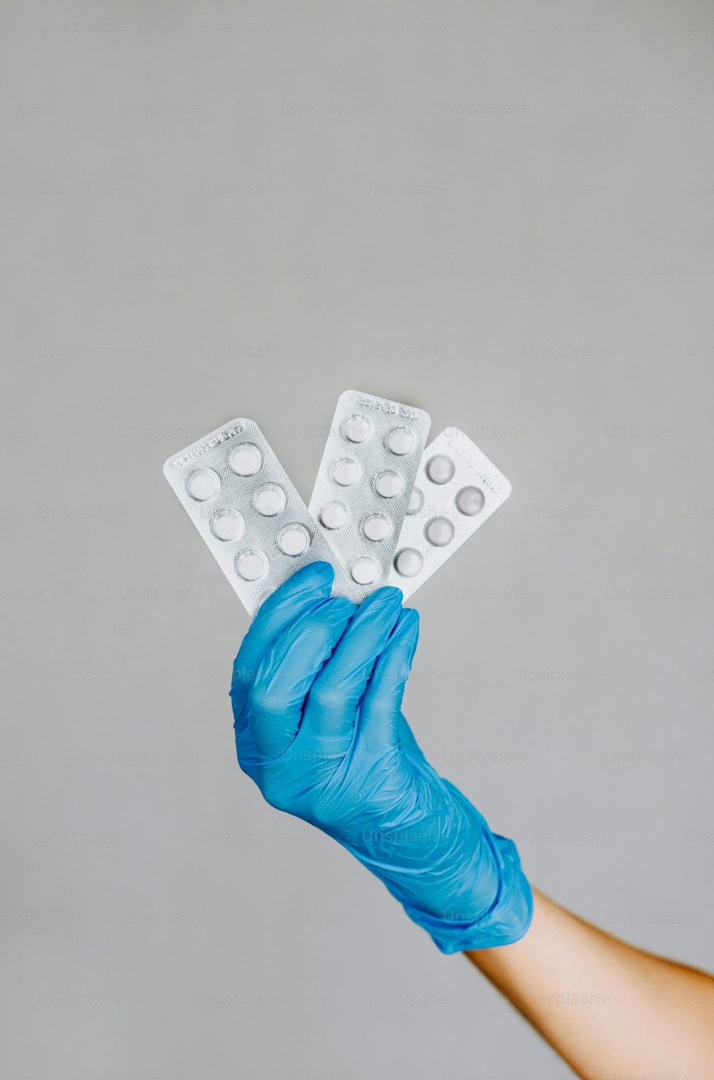a person in blue gloves holding two pills