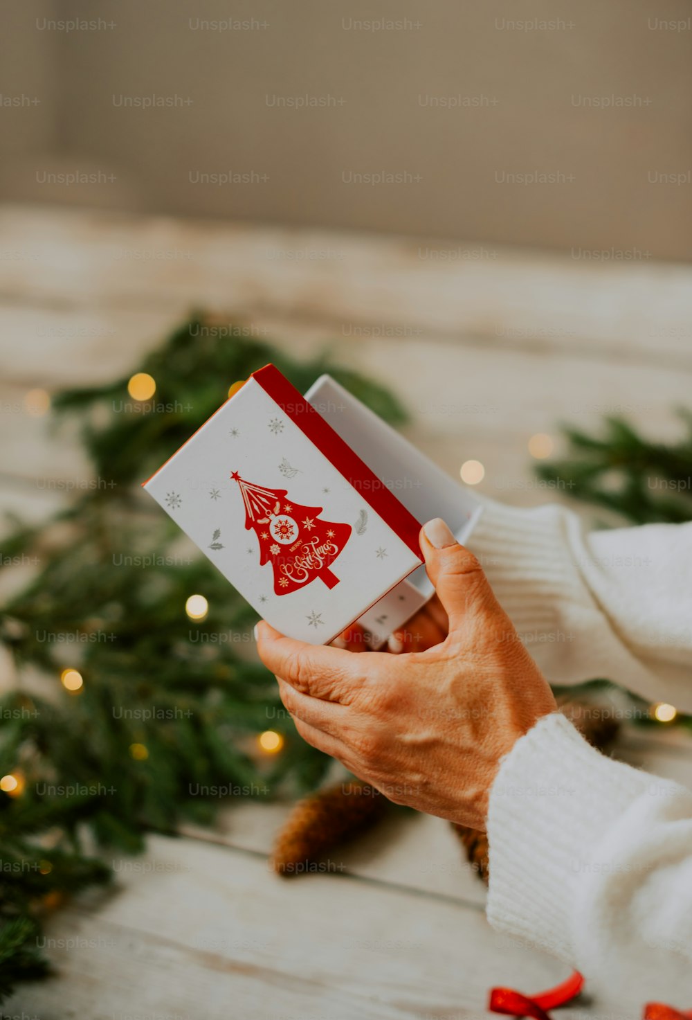 a person holding a christmas card in front of a christmas tree