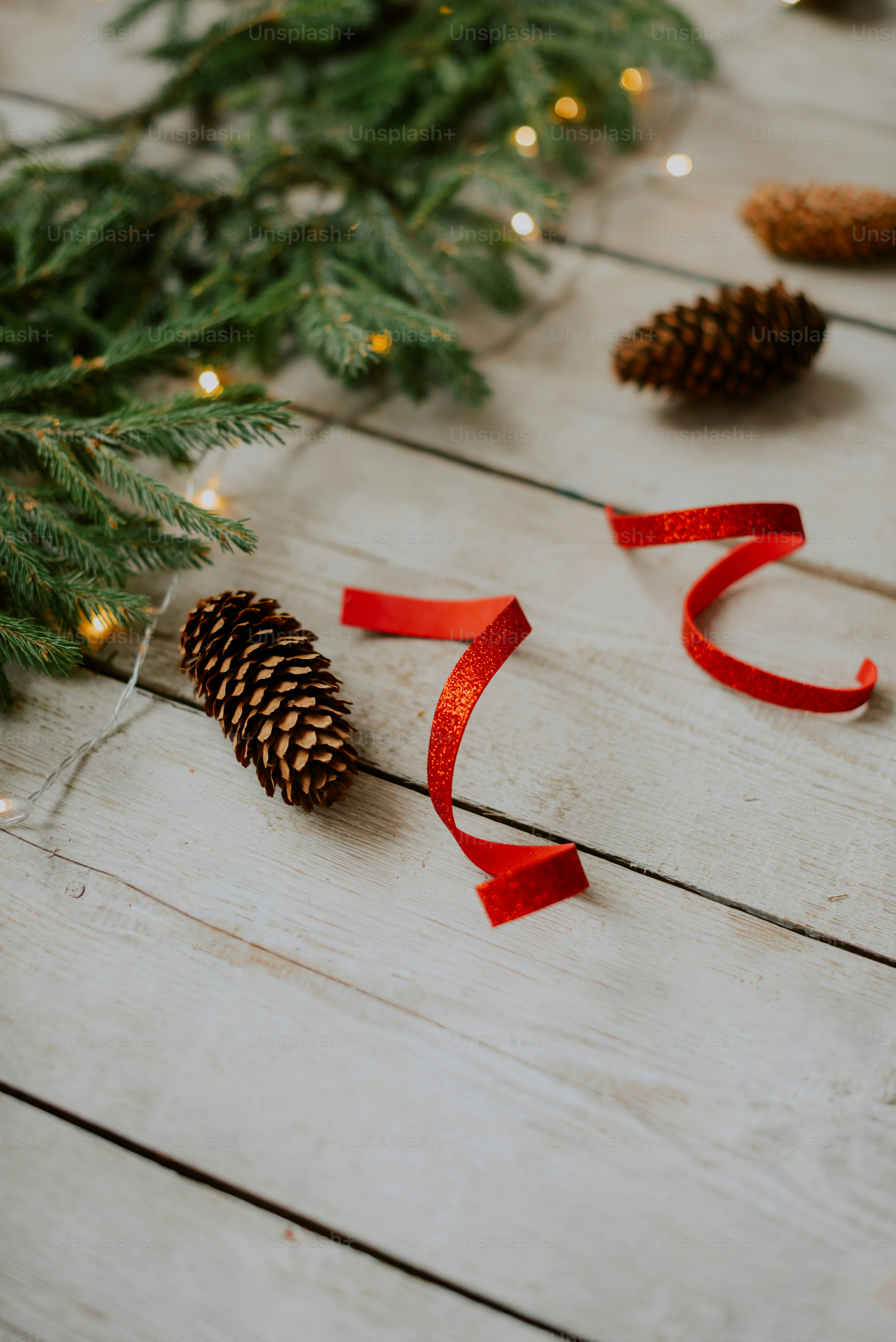 a pine cone and red ribbon on a wooden table