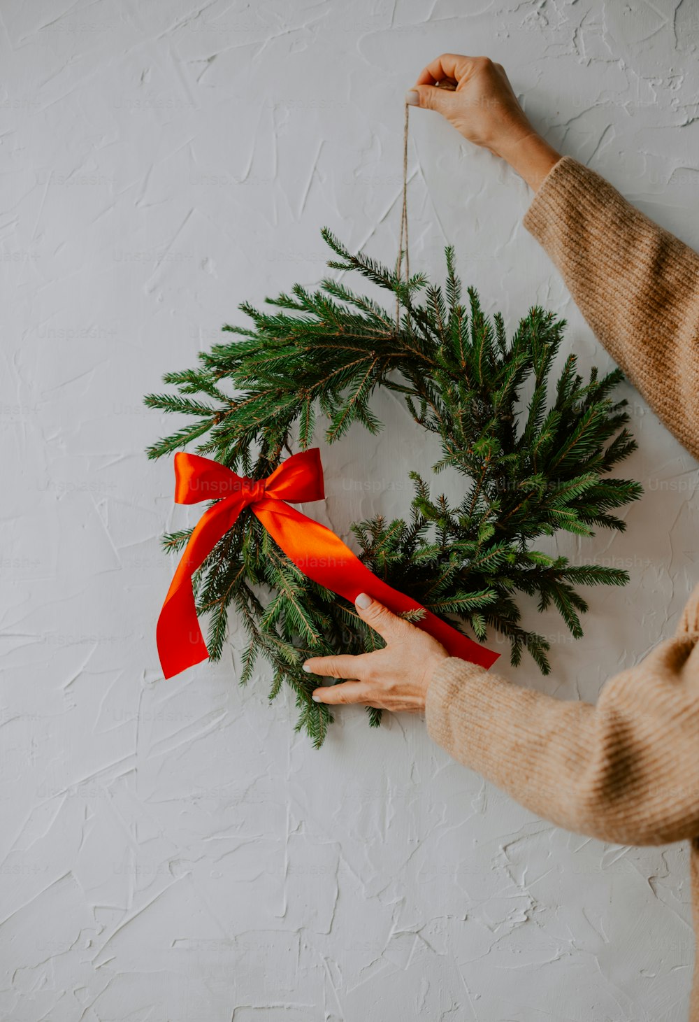a person holding a christmas wreath on a wall