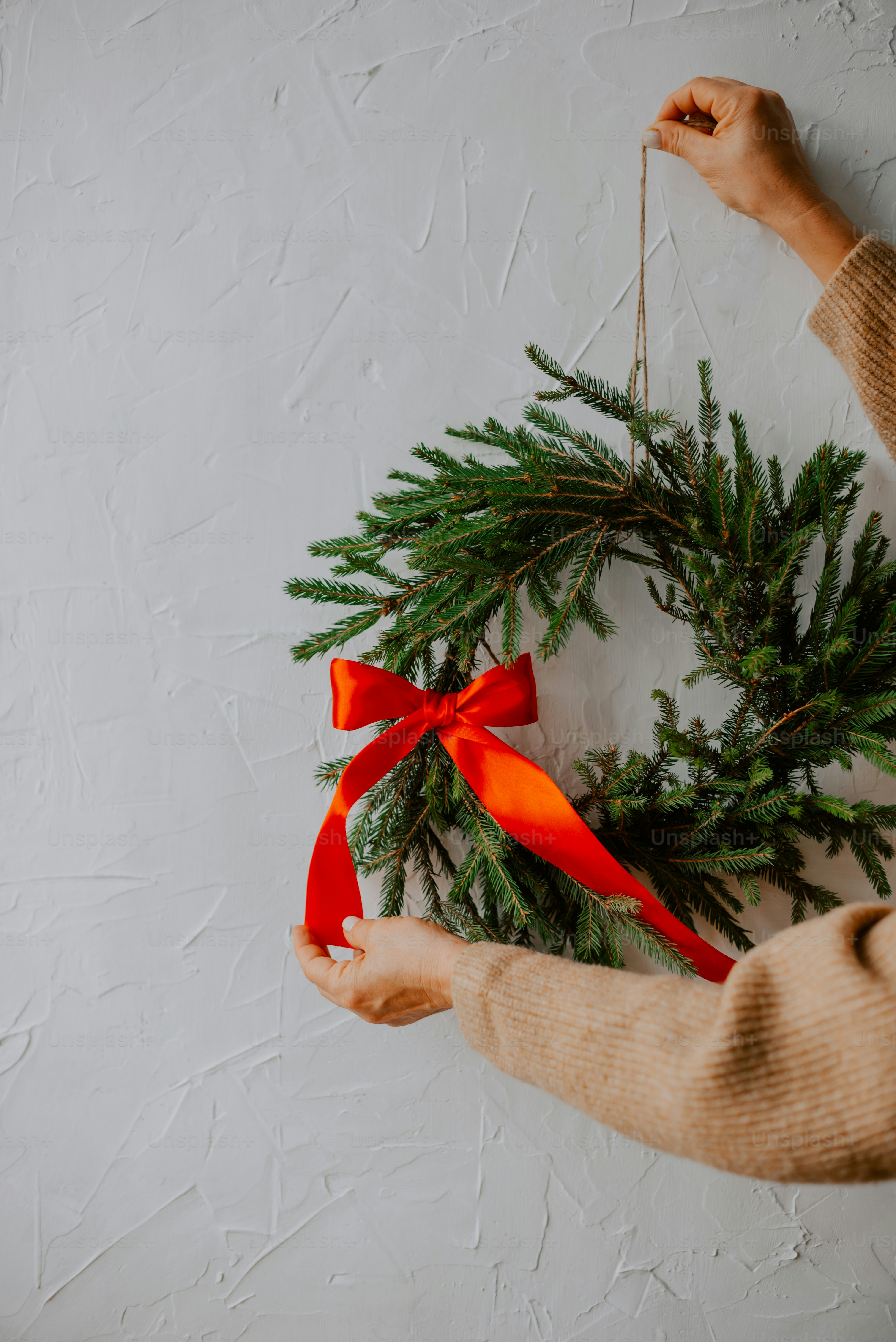 a person holding a christmas wreath on a wall