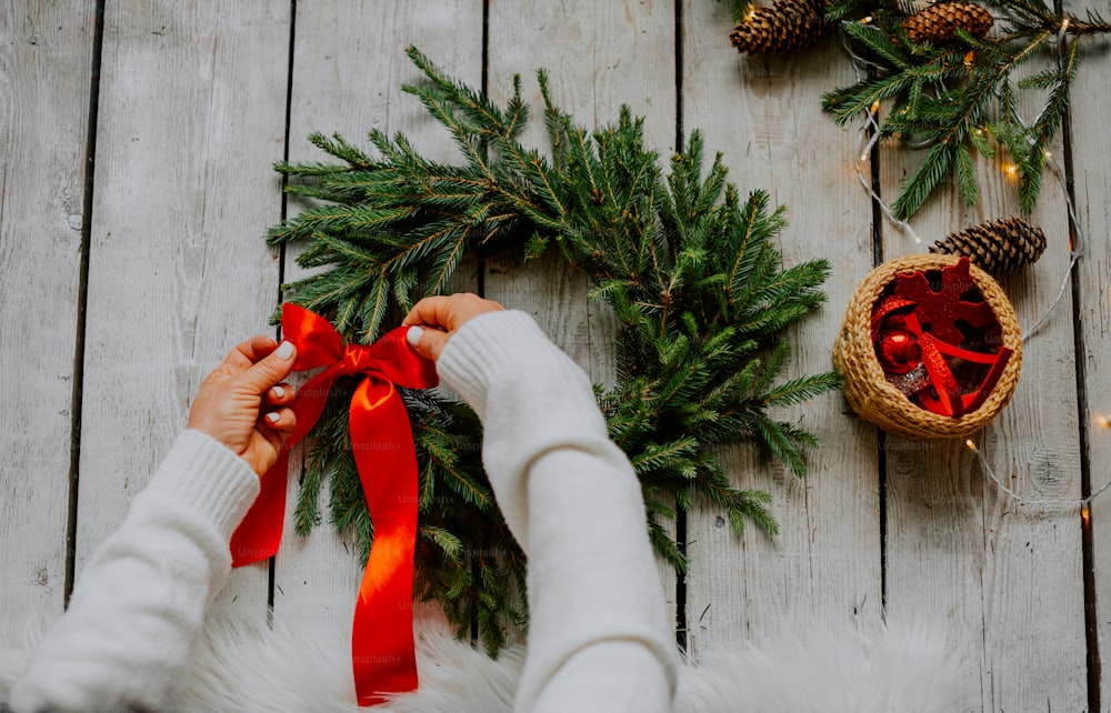a person holding a red ribbon over a wreath