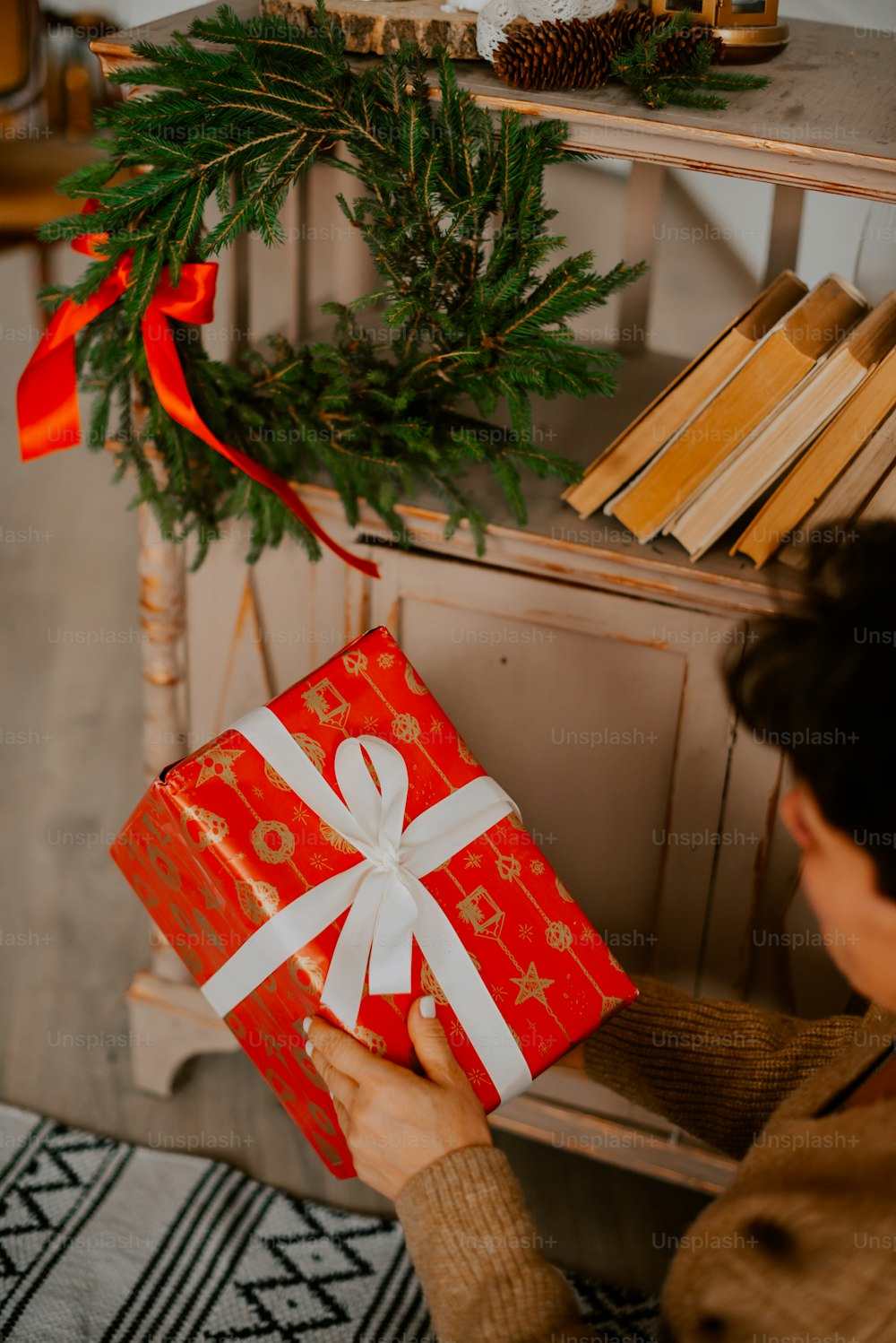 Una mujer sosteniendo una caja de regalo roja con una cinta blanca