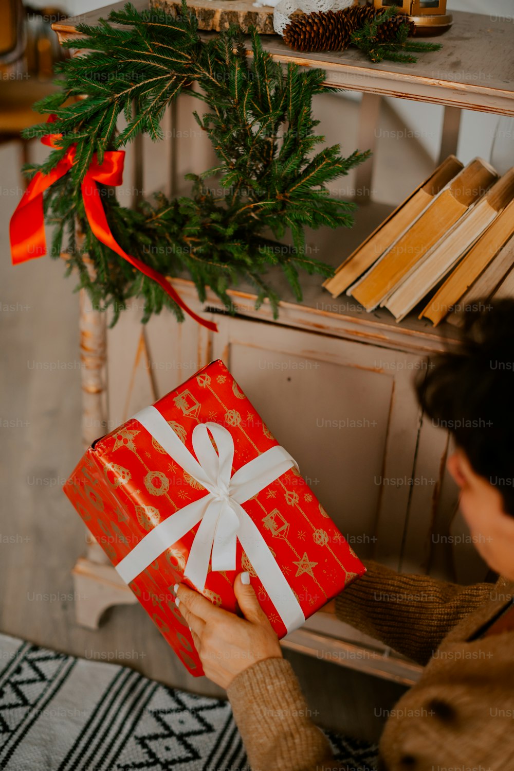 a woman holding a red gift box with a white ribbon