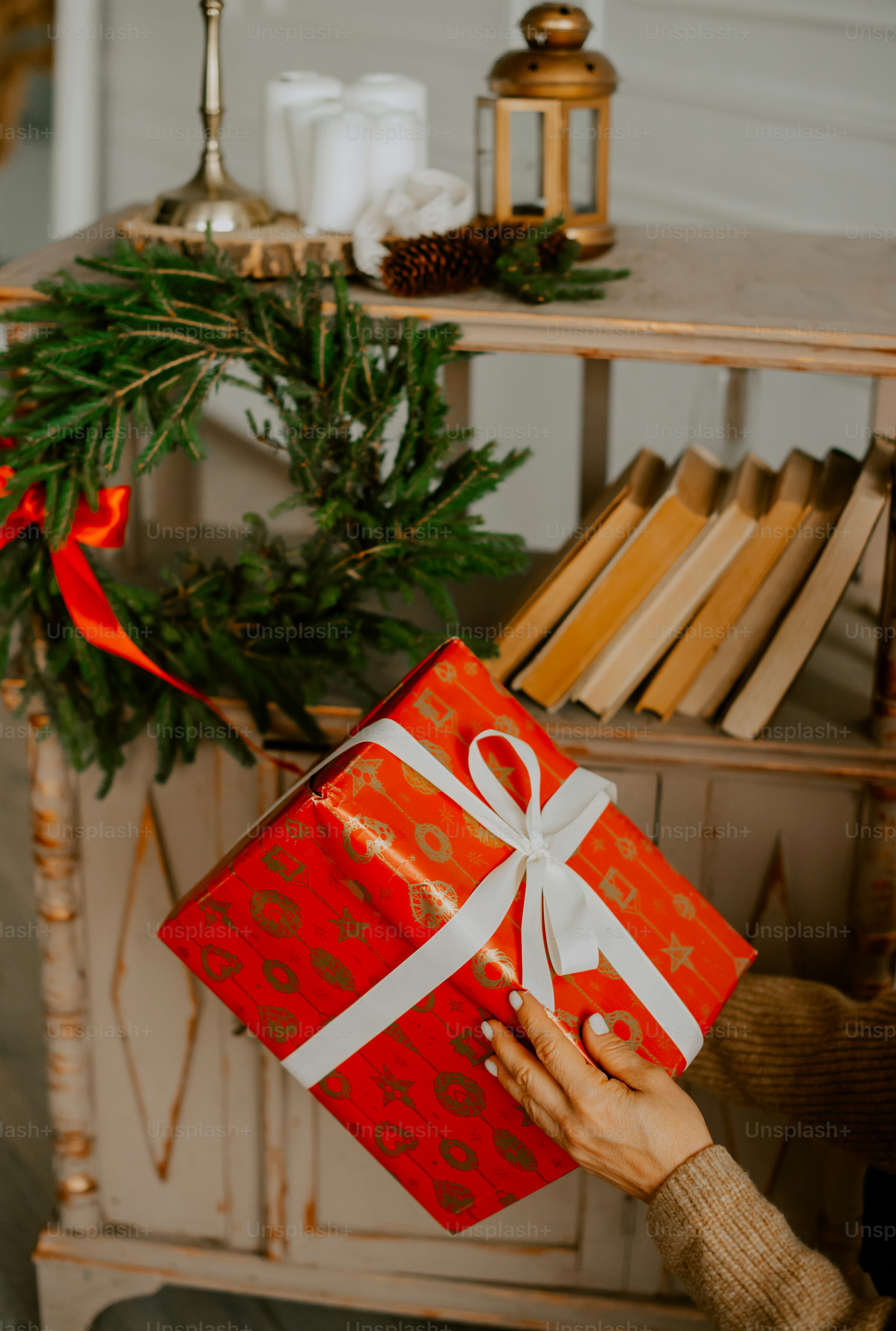 a person holding a red gift box with a white ribbon