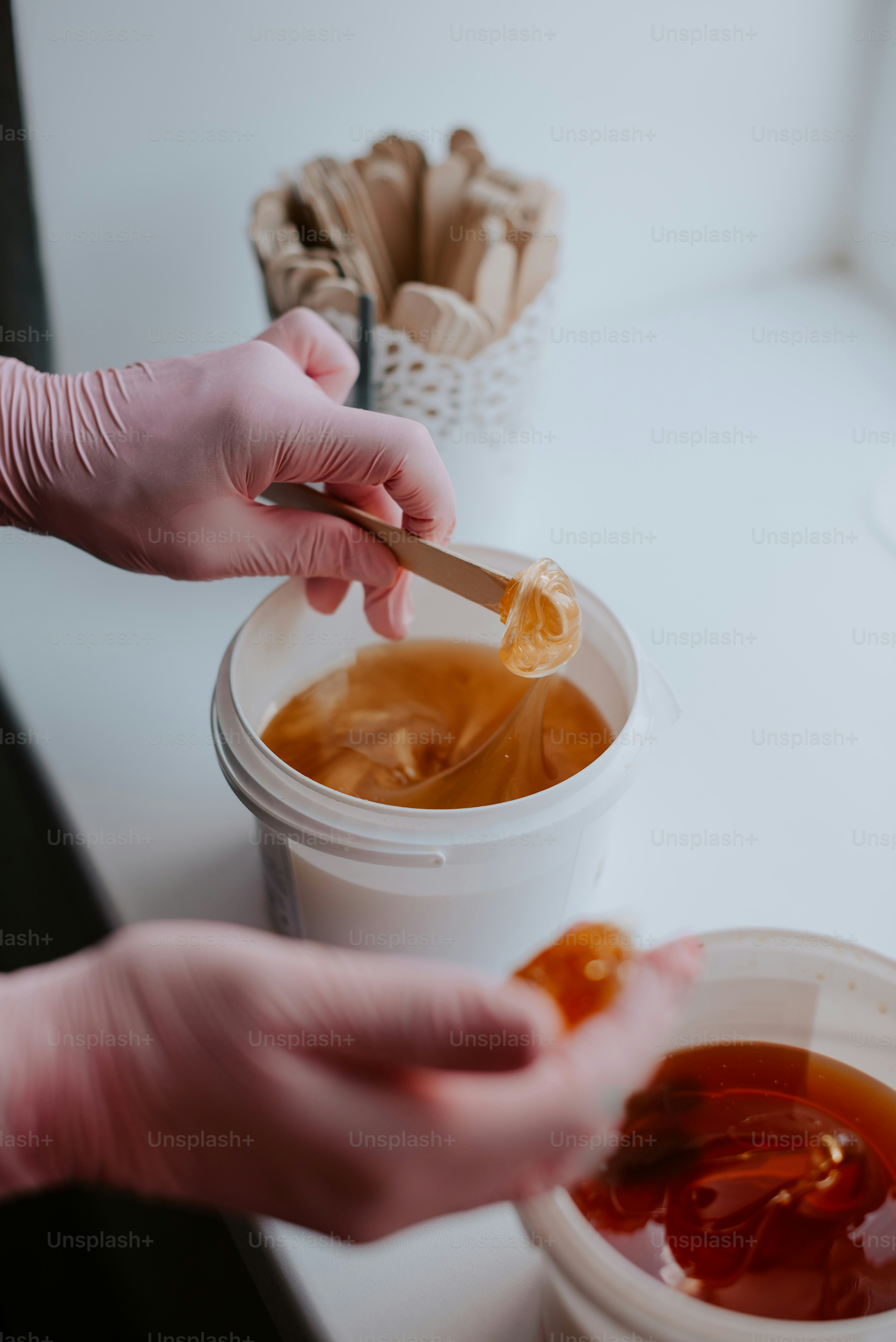 a person holding a spoon over a cup of liquid