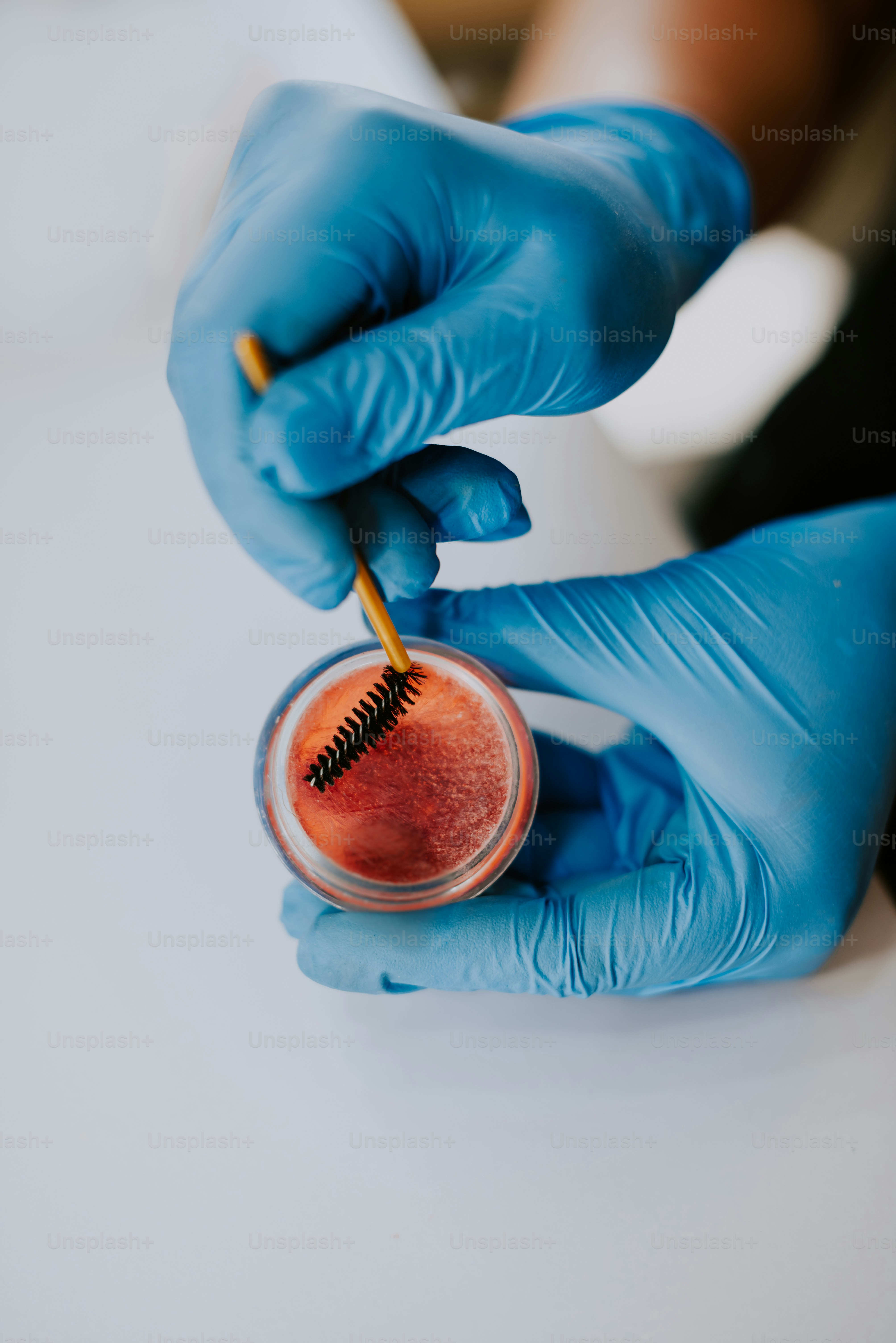a person in blue gloves is holding a small jar