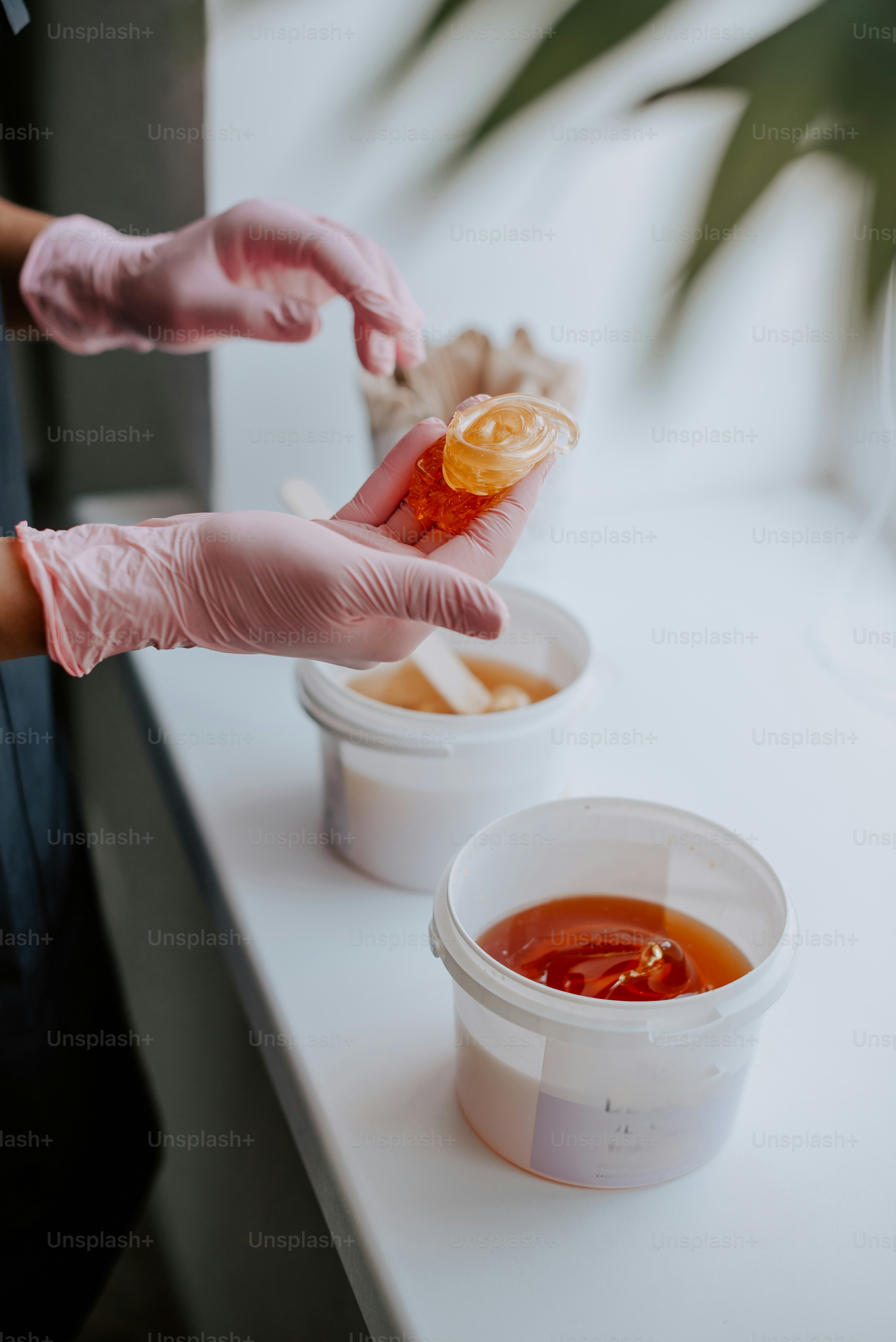 a person in pink gloves is putting sauce in a container