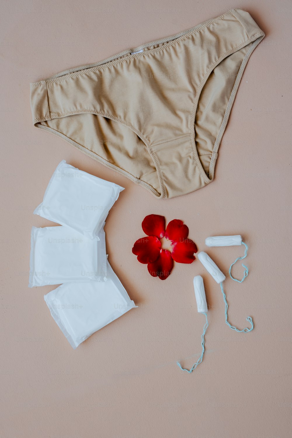 a pair of underwear and a flower on a pink surface